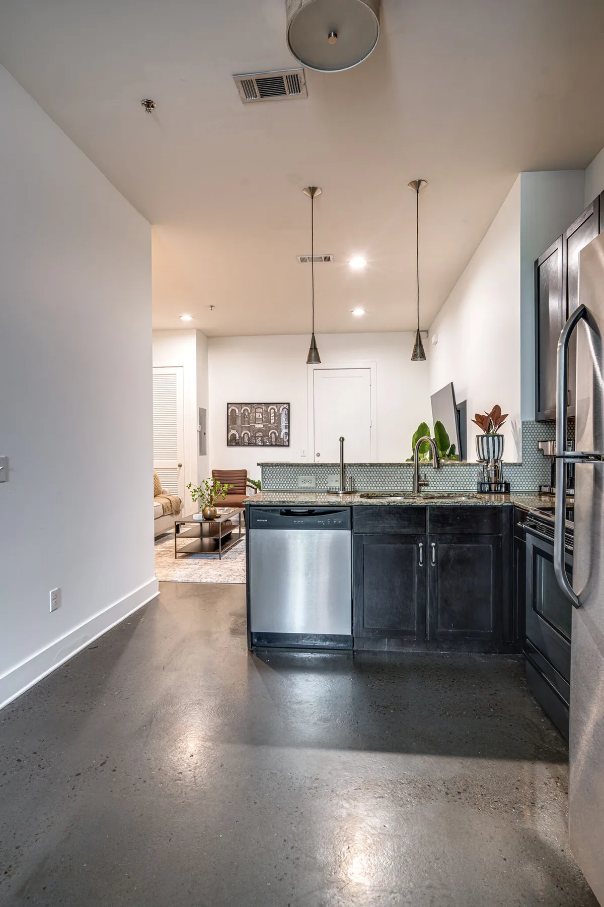 Featuring a contemporary kitchen space with a central island, this image highlights modern stainless steel appliances and hanging light fixtures. Decorative wall art adds visual interest, while the kitchen island provides space for entertaining and casual dining.