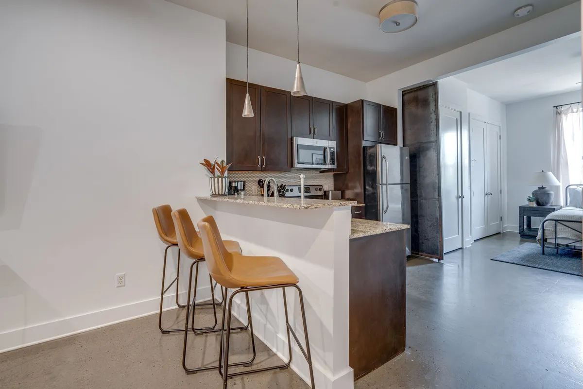 A bright, open kitchen area with bar stools at the kitchen island, sleek countertop appliances, and an airy, open layout. The space feels inviting and well-appointed, ideal for starting your stay with thoughtful amenities.