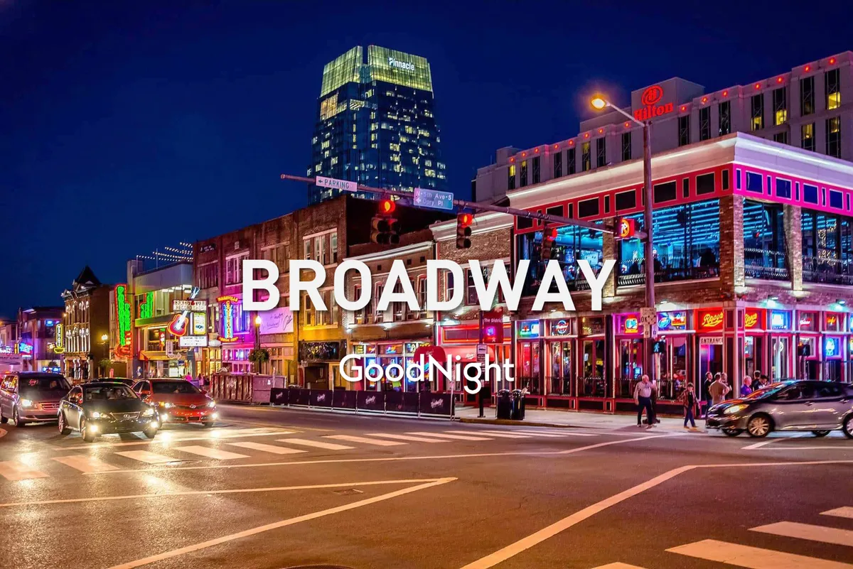 A bustling nighttime exterior with bright neon signs, busy street activity, and a variety of storefronts. The energy and lights capture the pulse of Nashville’s famed nightlife, with venues that promise live music, late-night dining, and cultural festivities.